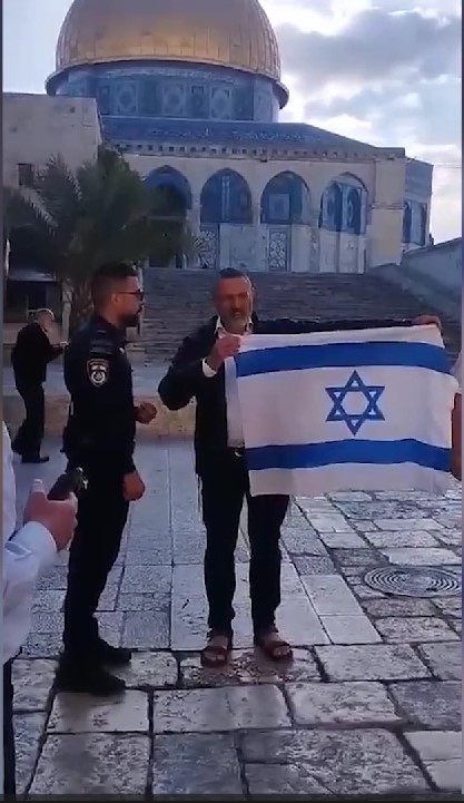 An Israeli illegal settler waves an Israeli flag as he enters Al-Aqsa Mosque